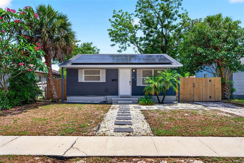 A single-story house with dark blue siding, a solar panel roof, and a stone walkway — 4616 9TH AVENUE S, ST PETERSBURG, FL