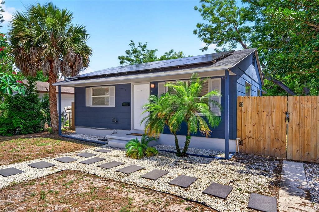 A blue house with solar panels on the roof features a gravel yard and walkway — 4616 9TH AVENUE S, ST PETERSBURG, FL