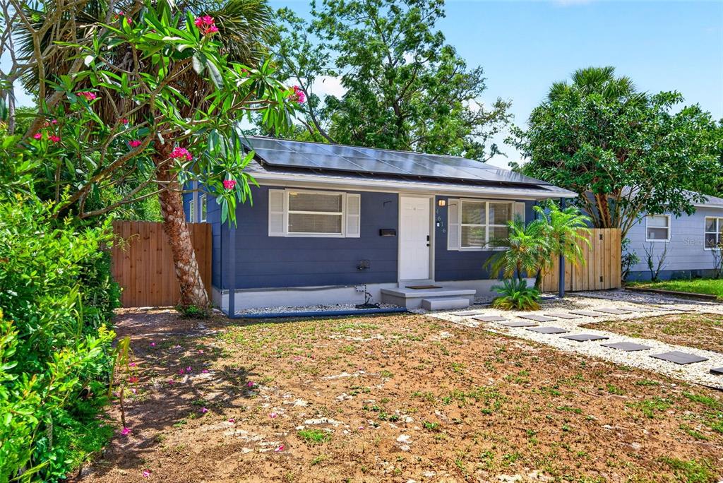 A blue single-story house features a solar panel roof, white trim, and a gravel driveway — 4616 9TH AVENUE S, ST PETERSBURG, FL