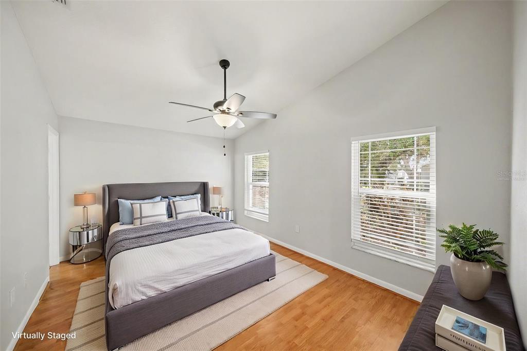 A bedroom with a gray upholstered bed, hardwood floors, and a ceiling fan — 2424 CAMDEN OAKS PLACE, VALRICO, FL