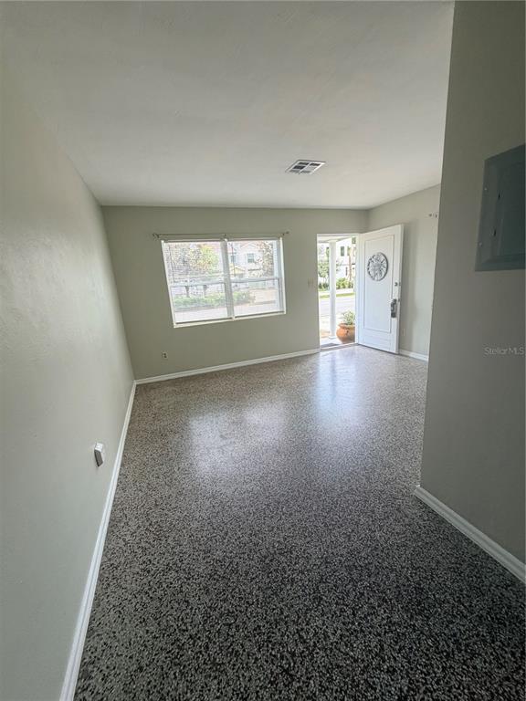An empty room features light-colored walls, a speckled epoxy floor, and a white front door — 13 W PRINCETON STREET UNIT 15, ORLANDO, FL