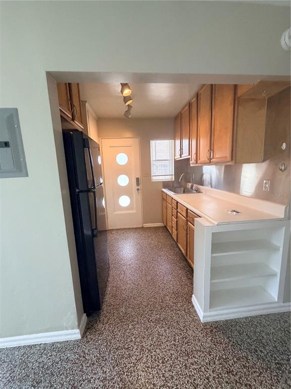 A galley kitchen features light wood cabinets, a black refrigerator, and a white exterior door — 13 W PRINCETON STREET UNIT 15, ORLANDO, FL
