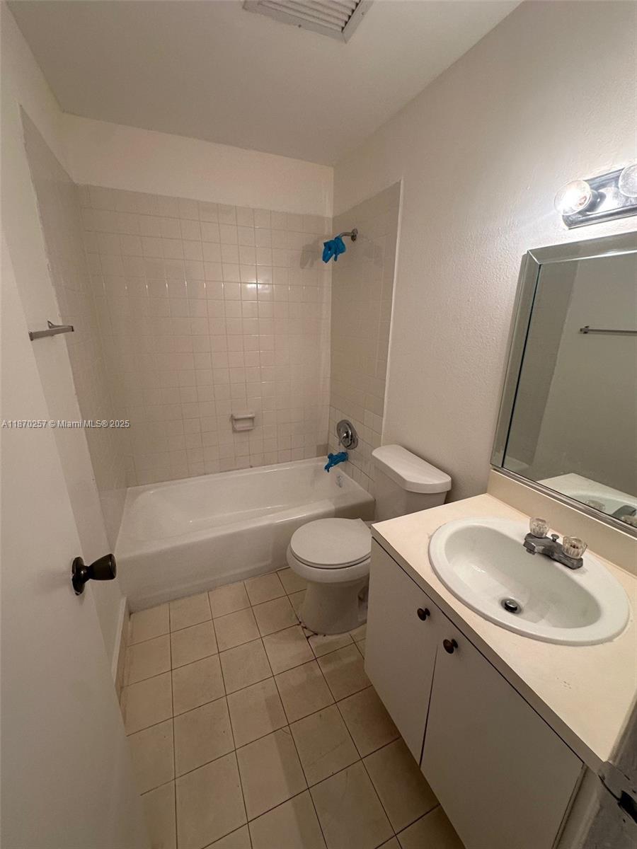 A bathroom features a white vanity, a toilet, and a shower-tub combination with tiled walls — 17911 NW 68th Ave # N206, Hialeah FL 33015, HIALEAH, FL