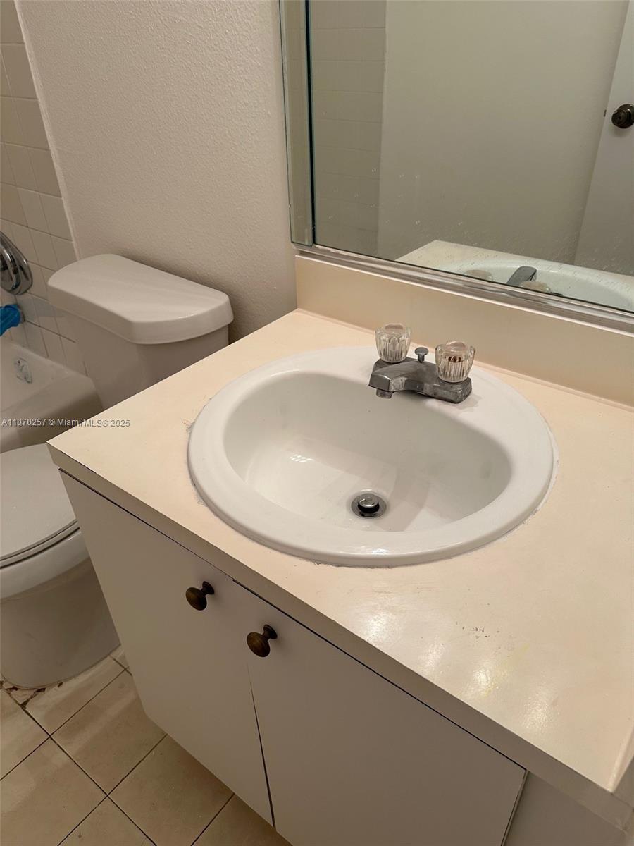 A bathroom features a white vanity with a sink, a toilet, and a wall mirror — 17911 NW 68th Ave # N206, Hialeah FL 33015, HIALEAH, FL