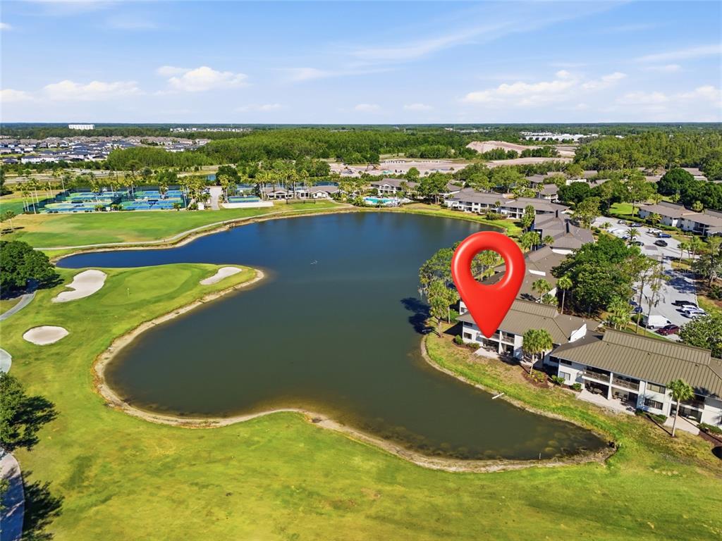 An aerial view shows a multi-story residential building situated beside a lake and golf course — 29300 BAY HOLLOW DRIVE UNIT 3257, WESLEY CHAPEL, FL