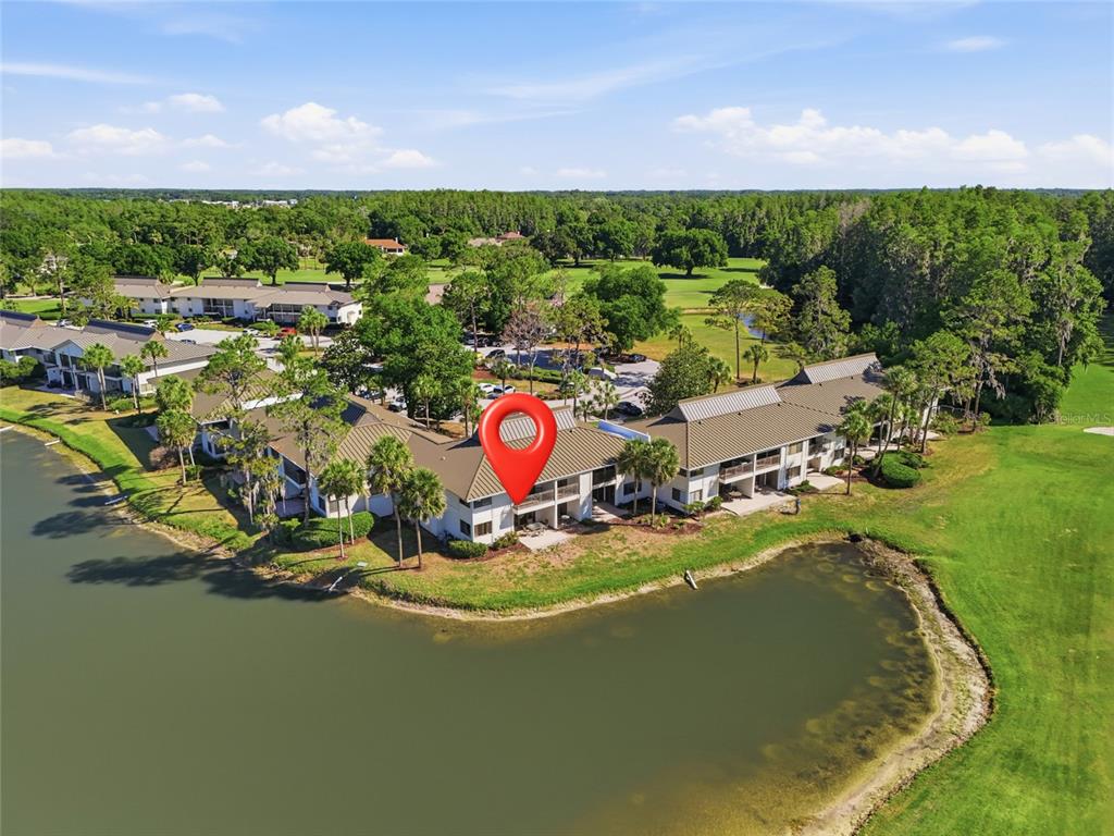 An aerial view shows a multi-story apartment building situated along a lake and golf course — 29300 BAY HOLLOW DRIVE UNIT 3257, WESLEY CHAPEL, FL
