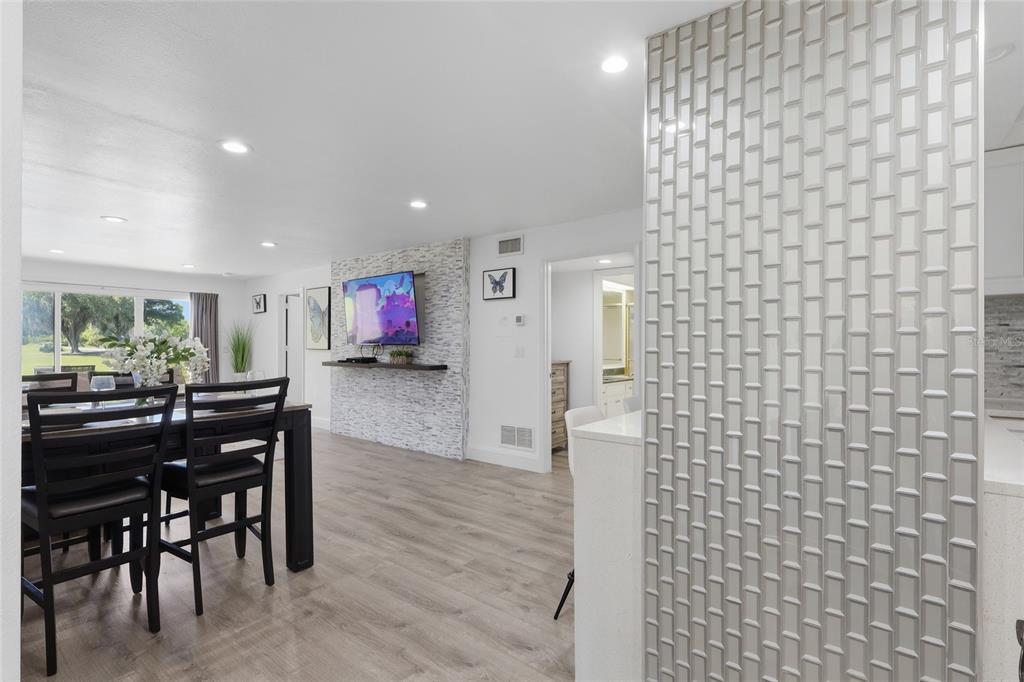 A dining area with wood-look flooring, a stone accent wall, and a tiled kitchen peninsula — 29300 BAY HOLLOW DRIVE UNIT 3257, WESLEY CHAPEL, FL