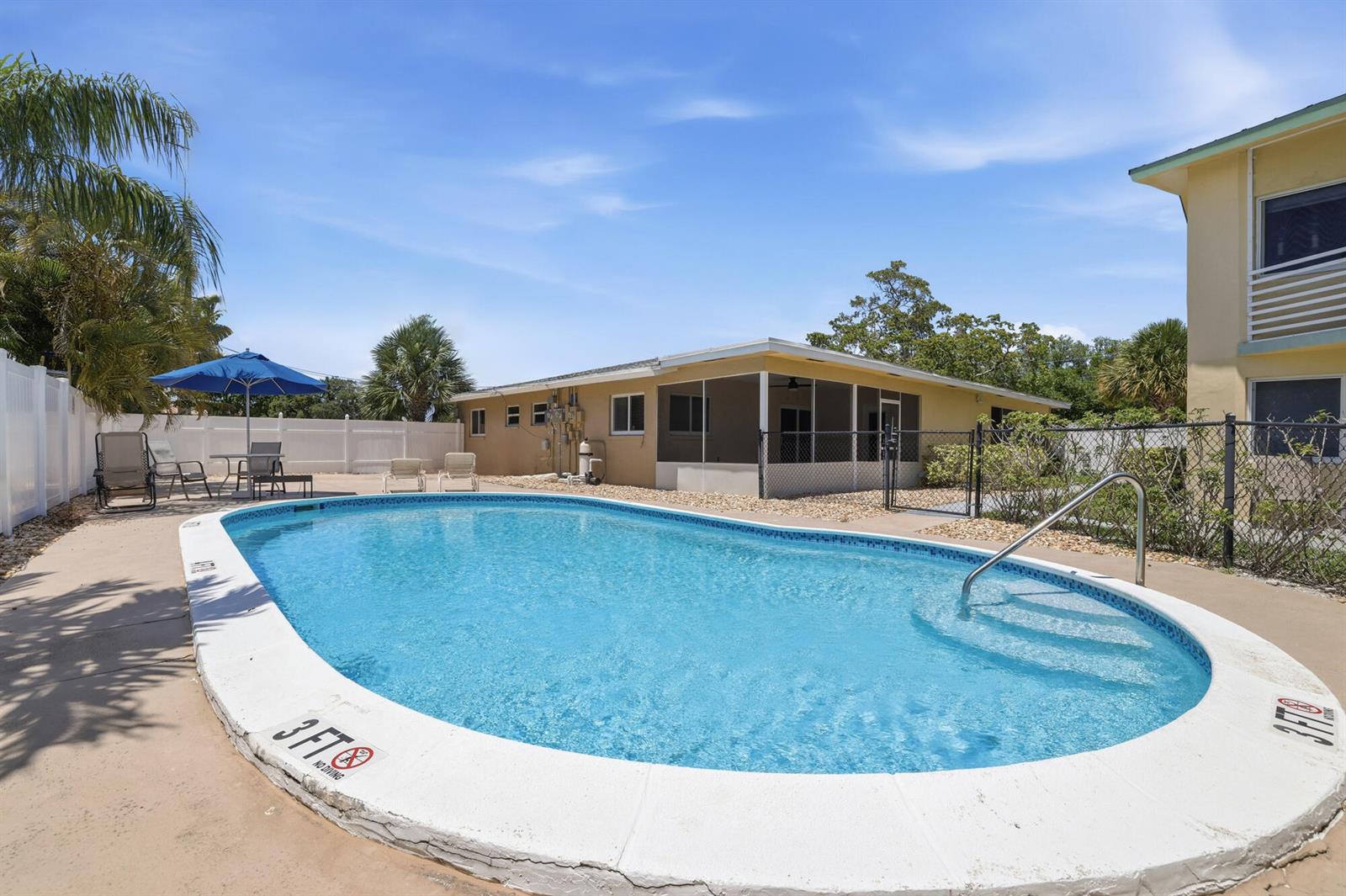An outdoor swimming pool with a white coping sits in a yard with a building — 1880 SE 3rd Street # 1880, Pompano Beach FL 33060, POMPANO BEACH, FL