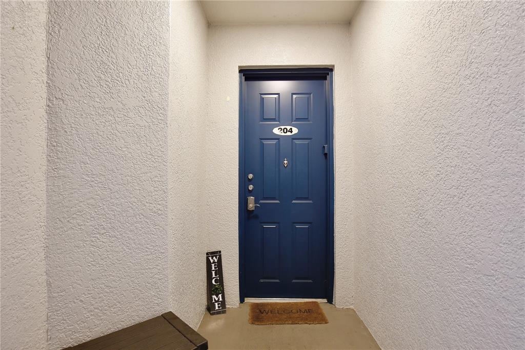 A blue front door with the number 204 is set in a textured white alcove — 5255 CANE ISLAND LOOP UNIT 204, KISSIMMEE, FL