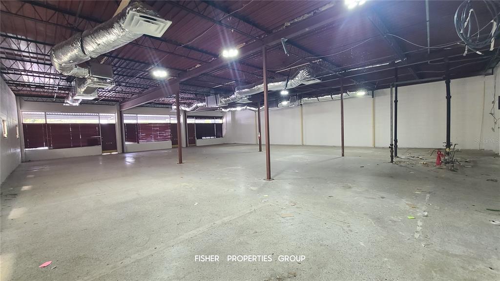 An open commercial space features exposed ceilings, concrete floors, and large windows with blinds — 211-213 E DAVIS BOULEVARD, TAMPA, FL