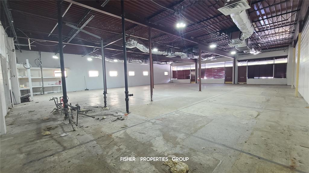 An expansive, unfinished commercial warehouse space features exposed ceiling ductwork, concrete floors, and support columns — 211-213 E DAVIS BOULEVARD, TAMPA, FL