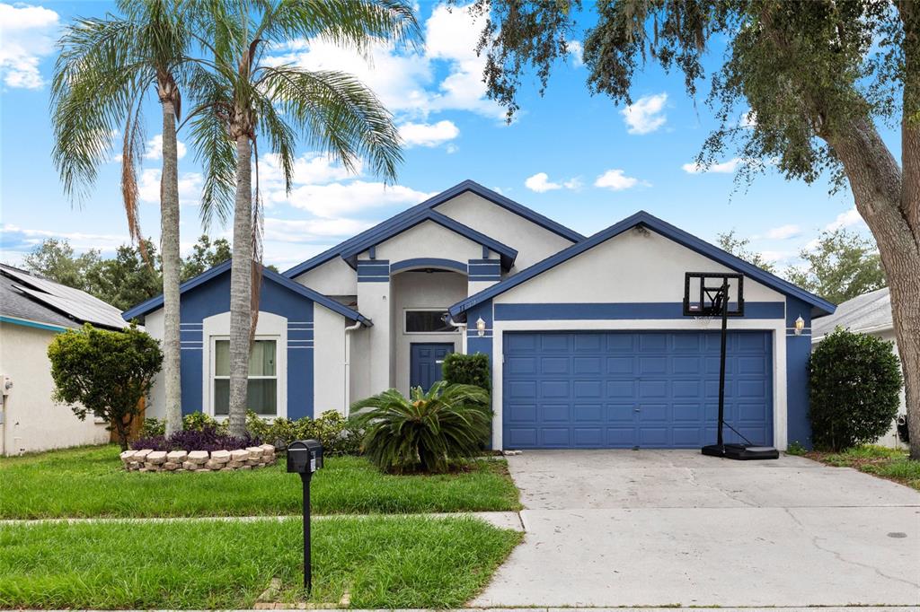 A single-story house with a blue and white exterior, a two-car garage, and palm trees — 11019 CONNACHT WAY, TAMPA, FL