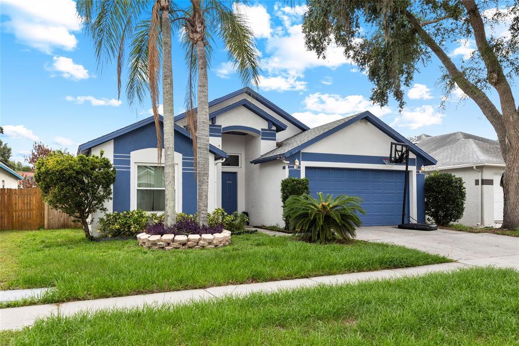 A single-story house with blue trim, a two-car garage, and palm trees in the yard — 11019 CONNACHT WAY, TAMPA, FL