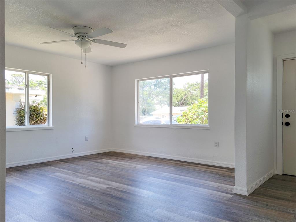 An empty room features white walls, wood-look flooring, a ceiling fan, and two windows — 1520 19TH AVENUE W, BRADENTON, FL