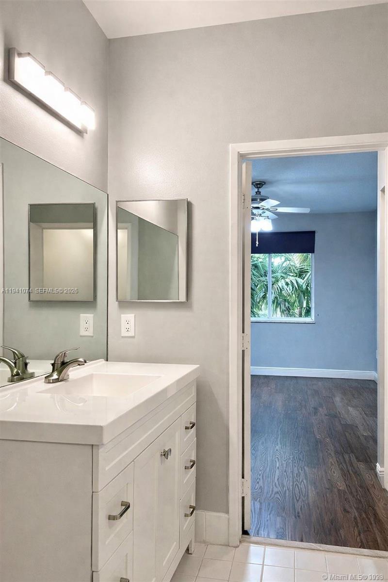 A bathroom with a white vanity, large mirror, and a doorway leading to a bedroom — 6928 SW 39th St # A304, Davie FL 33314, DAVIE, FL