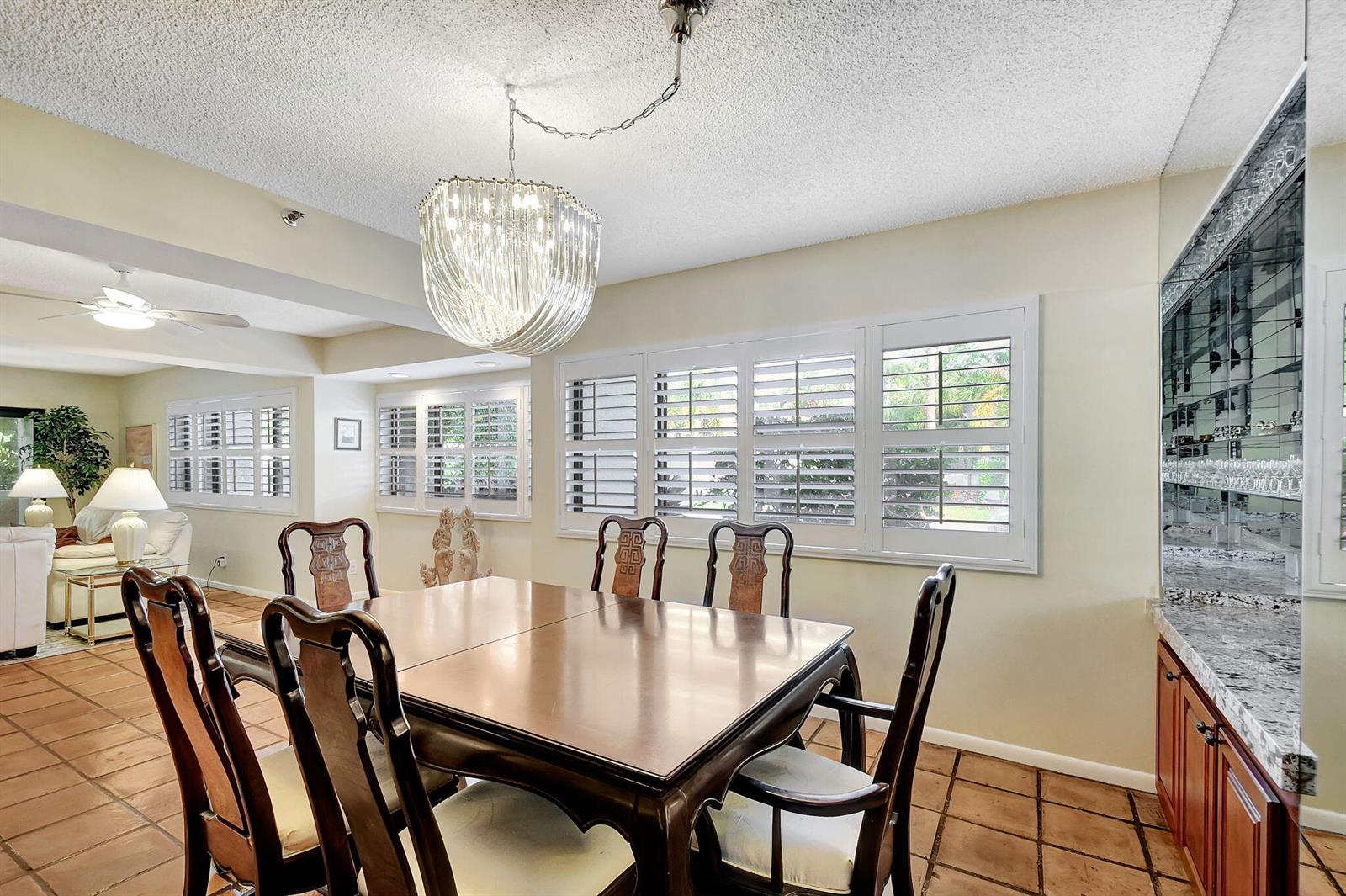 A dining room features a wooden table, six chairs, a crystal chandelier, and tiled floors — 318 Oak Harbour Drive # 318, Juno Beach FL 33408, JUNO BEACH, FL