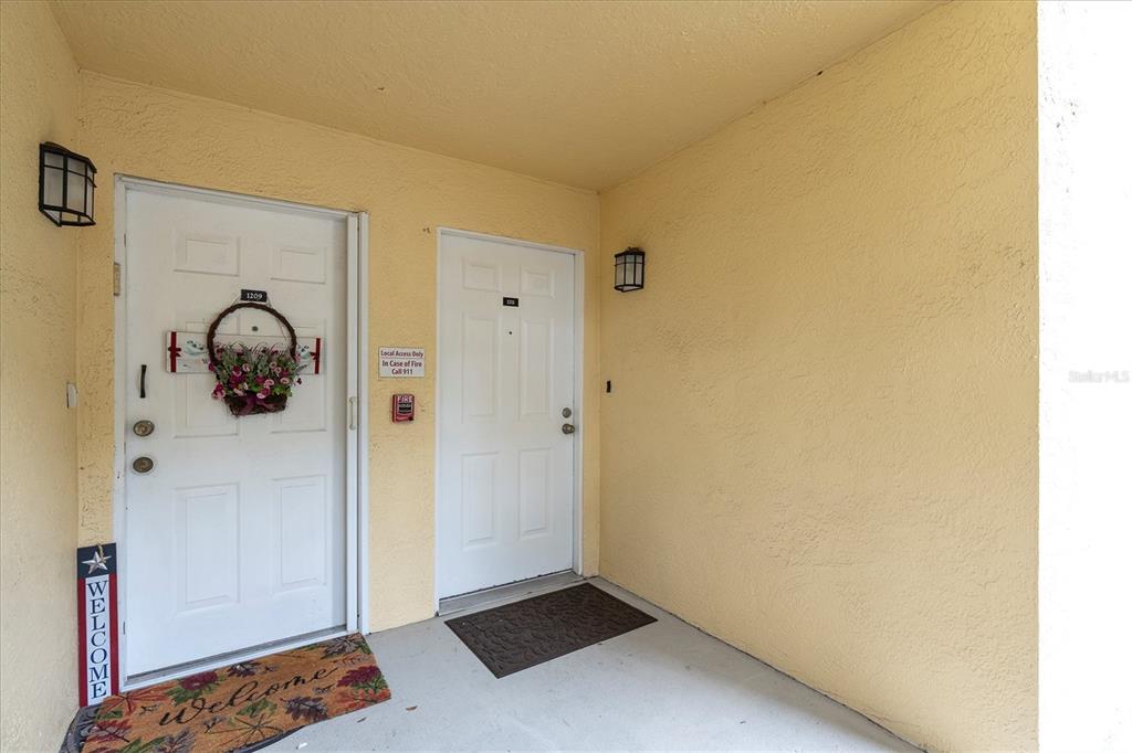 An exterior view of a building entrance featuring two white doors and a welcome mat — 3001 58TH AVENUE S UNIT 1211, ST PETERSBURG, FL