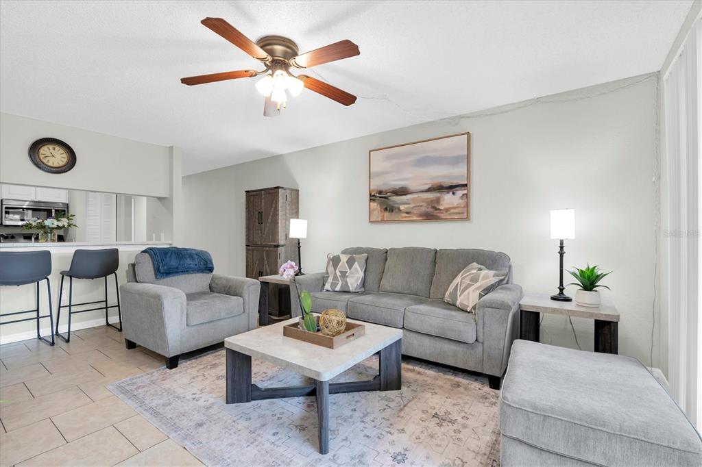 A living room features a grey sofa, matching armchair, coffee table, and a ceiling fan — 3001 58TH AVENUE S UNIT 1211, ST PETERSBURG, FL