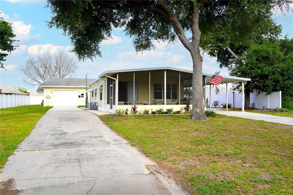 A single-story house with a screened-in porch, a concrete driveway, and a detached garage — 5747 E LAKE FOX DRIVE, WINTER HAVEN, FL