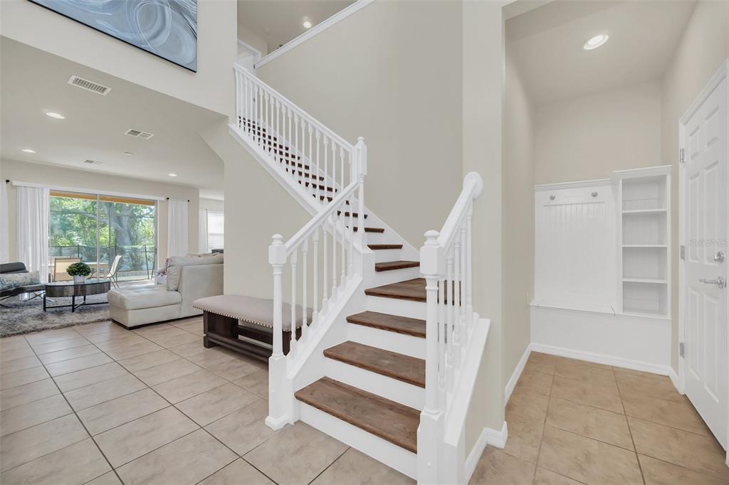 An entryway features a wooden staircase, tile flooring, and a built-in bench with shelving — 1917 NICE COURT, KISSIMMEE, FL