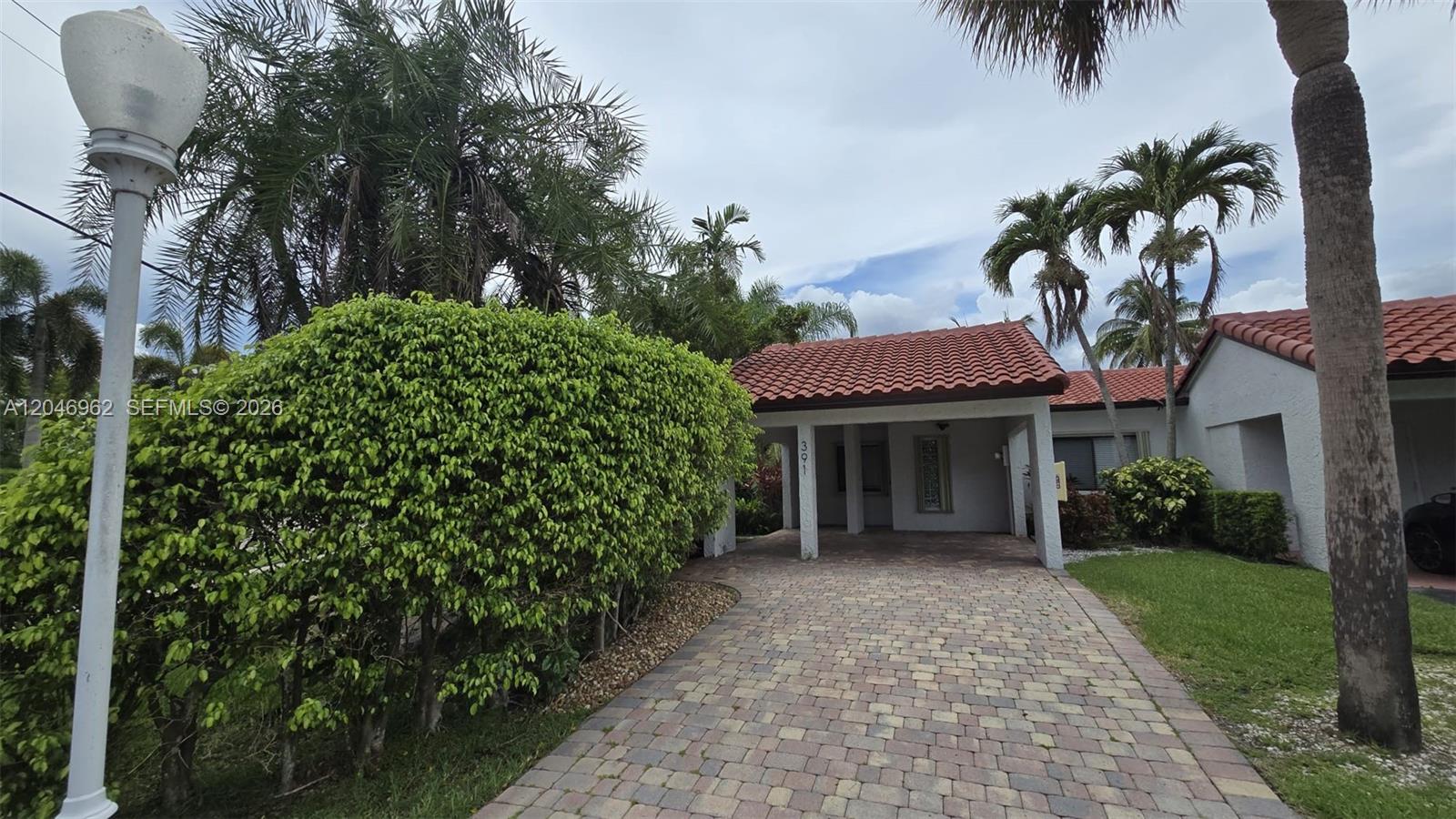 A paved driveway leads to a covered entrance of a house with a tiled roof — 391 Ivy Ln # 1, Weston FL 33326, WESTON, FL