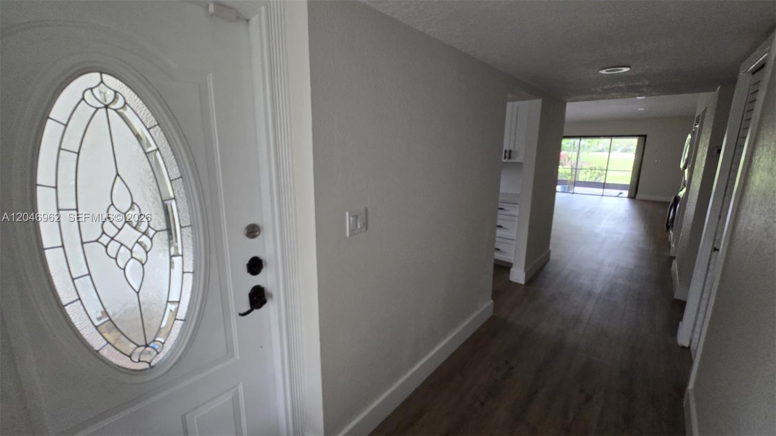 An entryway with a white oval-glass door leads into a hallway with wood-look flooring — 391 Ivy Ln # 1, Weston FL 33326, WESTON, FL