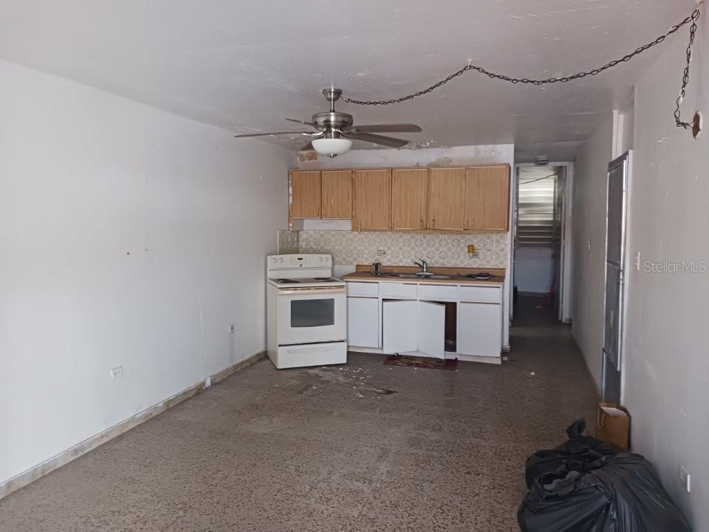 An interior view of a kitchen with white cabinets, a white stove, and a ceiling fan — 4219 CALLE SANTA MONICA, PONCE, PR