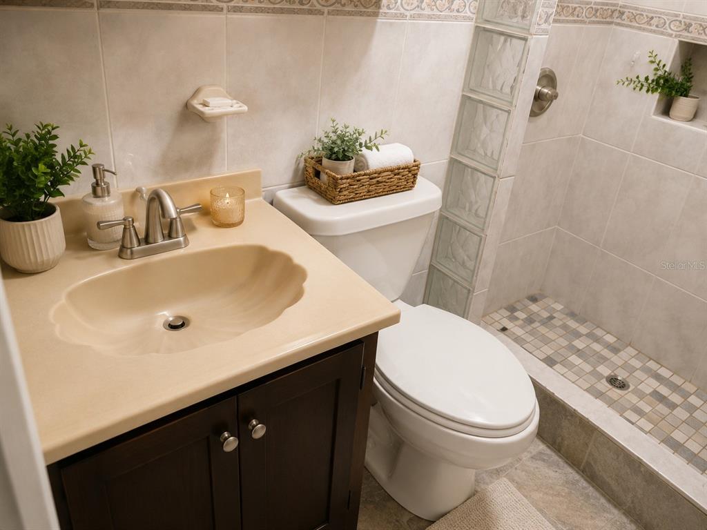 A bathroom features a dark wood vanity, beige countertop, white toilet, and a tiled shower — 4219 CALLE SANTA MONICA, PONCE, PR