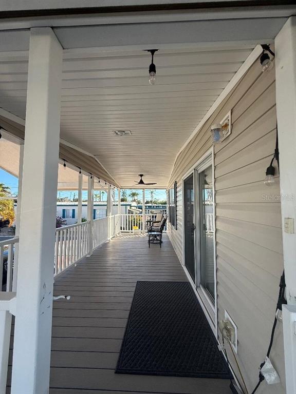 A covered outdoor deck features gray composite flooring, white railings, and string lighting — 1375 PASADENA AVENUE S UNIT 217, SOUTH PASADENA, FL