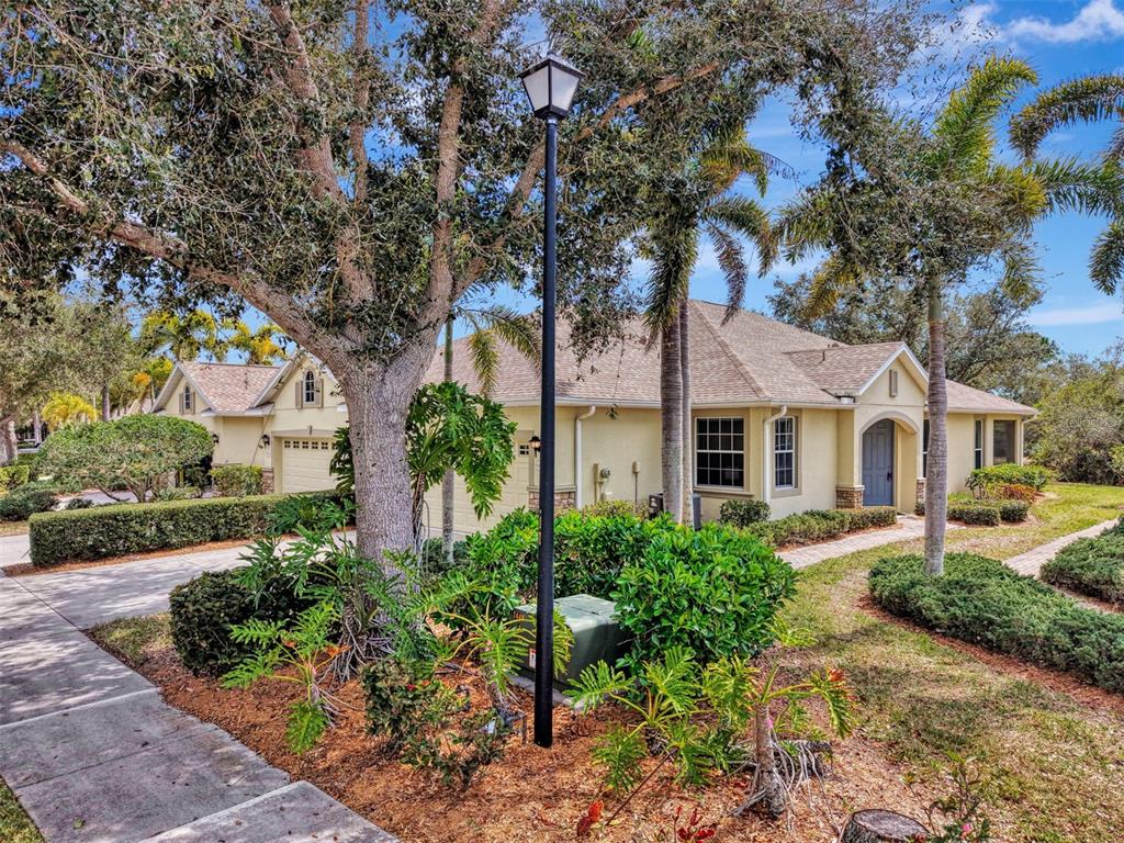 A single-story house with a beige exterior, a shingled roof, and a landscaped front yard — 9367 CARNABY DRIVE, VENICE, FL