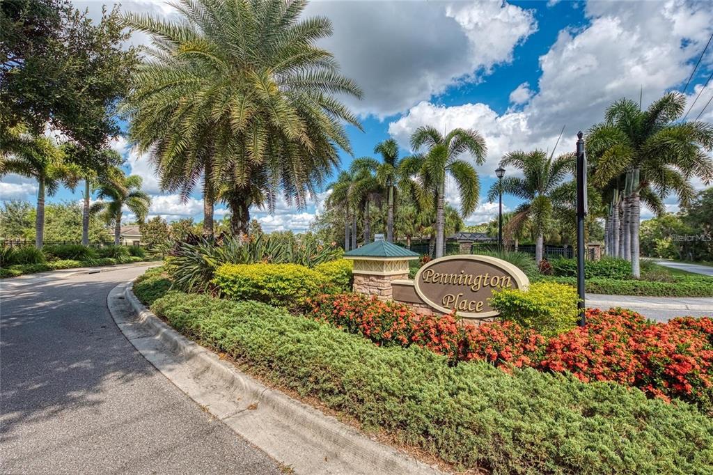A stone monument sign for Pennington Place sits amidst lush landscaping and palm trees — 9367 CARNABY DRIVE, VENICE, FL