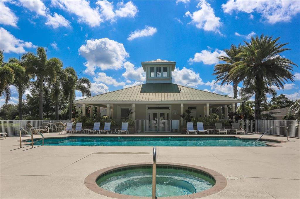 A swimming pool and hot tub sit in front of a community clubhouse with palm trees — 9367 CARNABY DRIVE, VENICE, FL