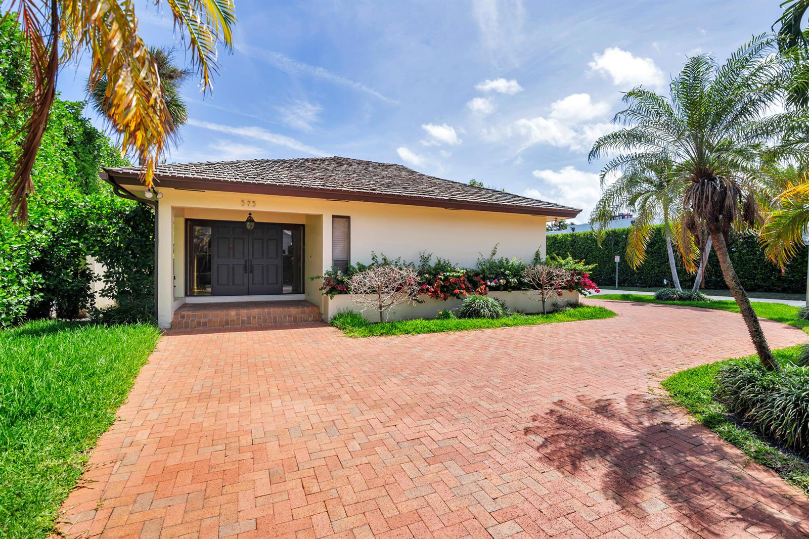 A single-story house with a brick driveway, palm trees, and a dark front door — 575 N Lake Way, Palm Beach FL 33480, PALM BEACH, FL