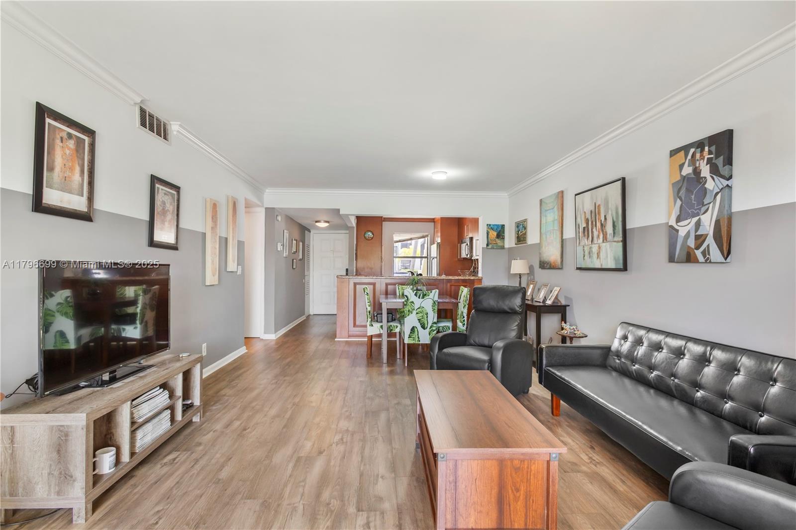 A living room features wood-look flooring, a black leather sofa, and a television console — 22053 Palms Way # 106, Boca Raton FL 33433, BOCA RATON, FL
