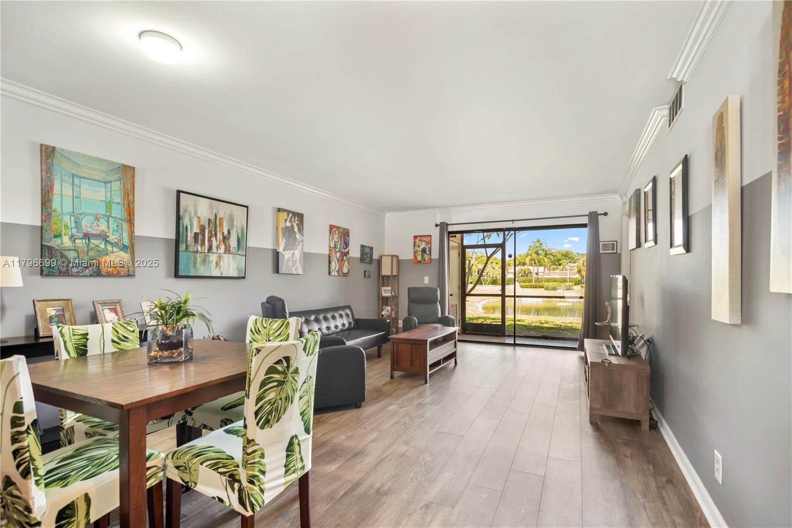 A living and dining area features wood-look flooring, two-tone walls, and a sliding glass door — 22053 Palms Way # 106, Boca Raton FL 33433, BOCA RATON, FL