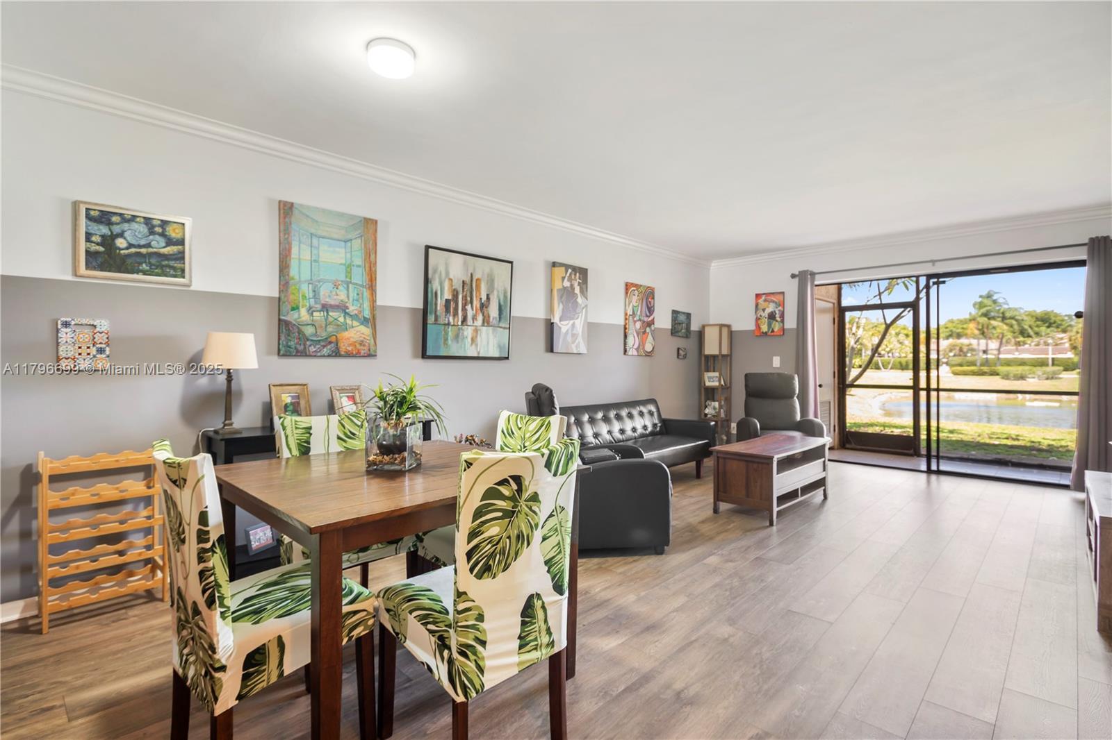A dining and living area features wood-look flooring, a two-tone wall, and a sliding glass door — 22053 Palms Way # 106, Boca Raton FL 33433, BOCA RATON, FL