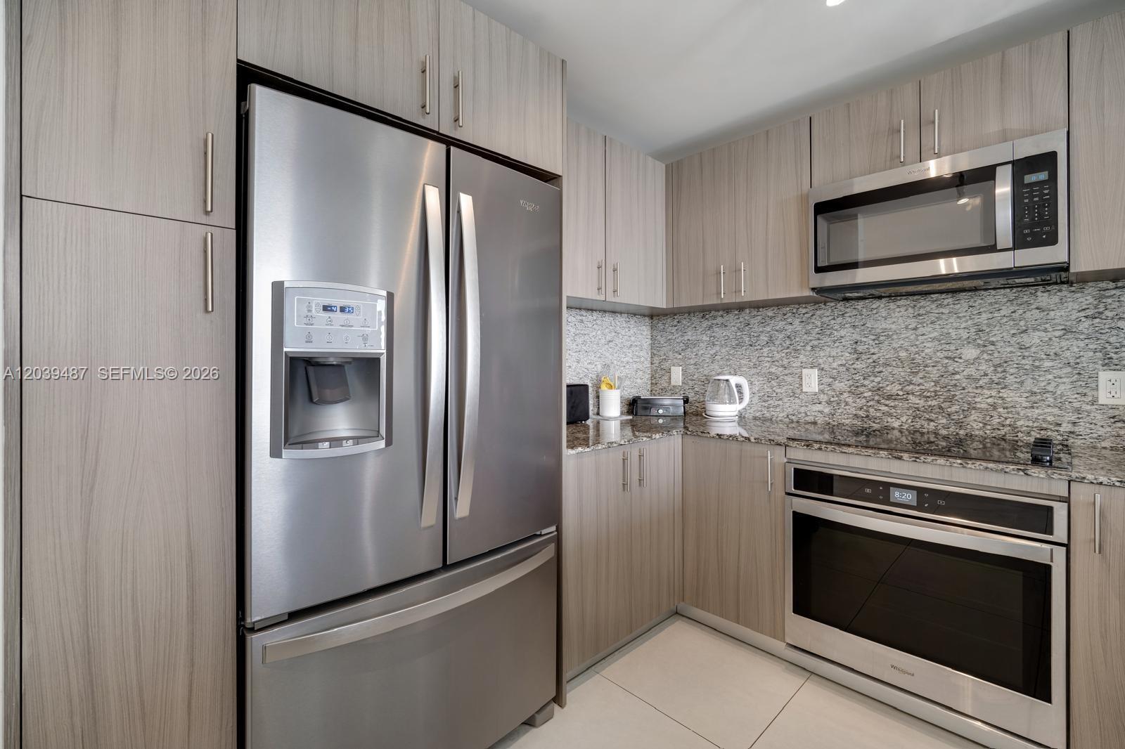 A modern kitchen featuring light wood cabinetry, stainless steel appliances, and granite countertops — 5350 NW 84th Ave # 909, Doral FL 33166, DORAL, FL