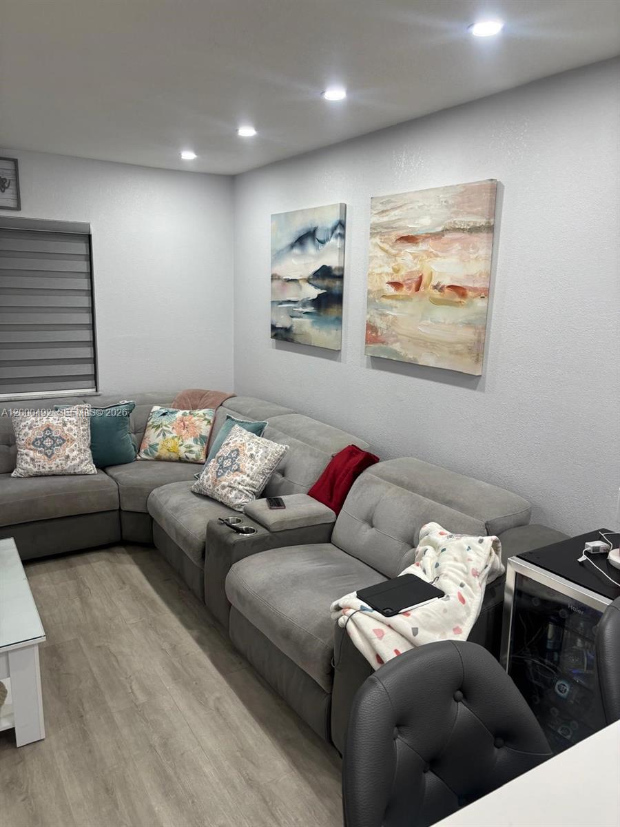 A living room features a gray sectional sofa, two abstract paintings, and light wood flooring — 4050 NW 135th St # 1, Opa-Locka FL 33054, OPA-LOCKA, FL