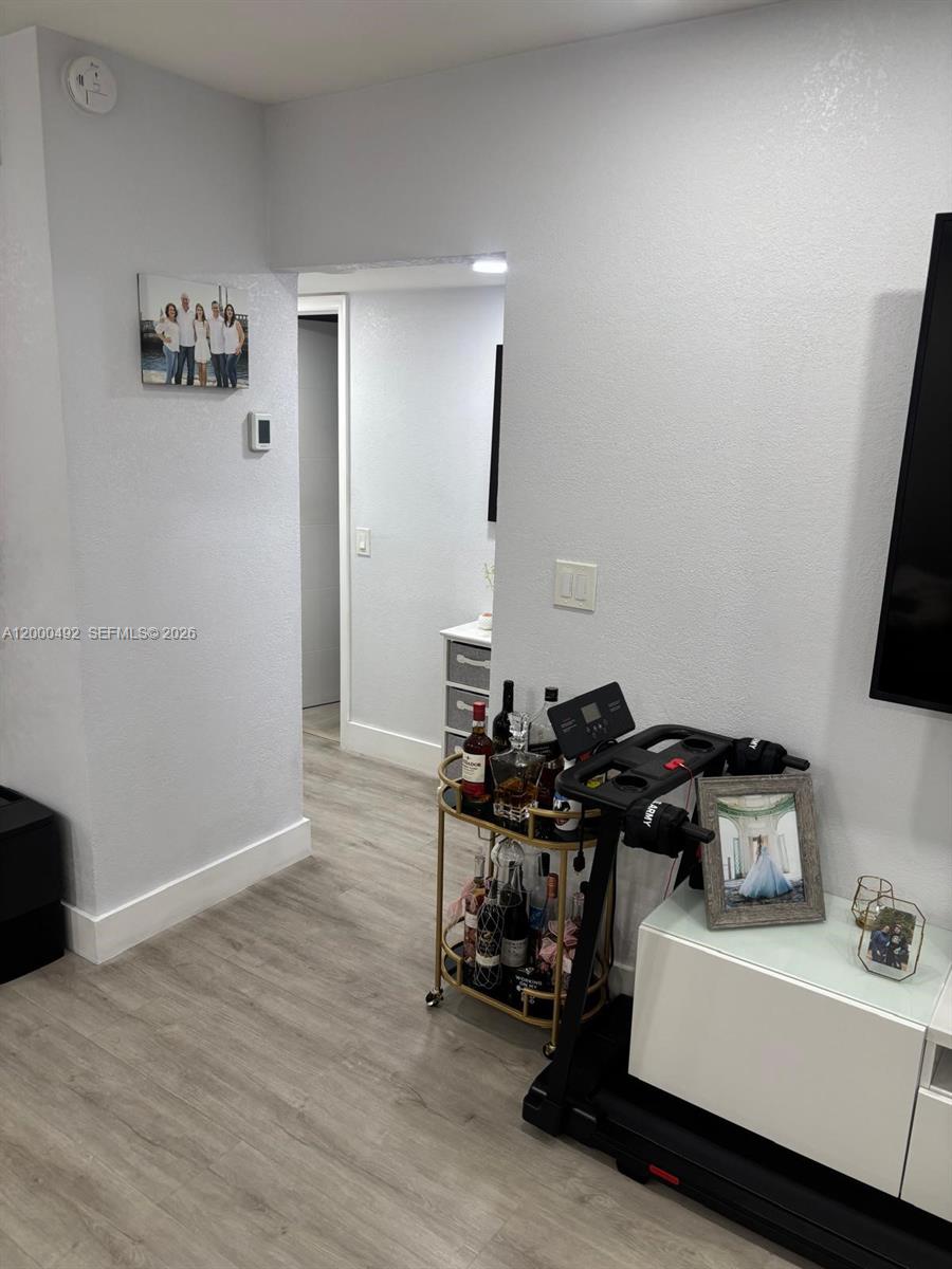 A room features light gray walls, wood-look flooring, a bar cart, and a treadmill — 4050 NW 135th St # 1, Opa-Locka FL 33054, OPA-LOCKA, FL