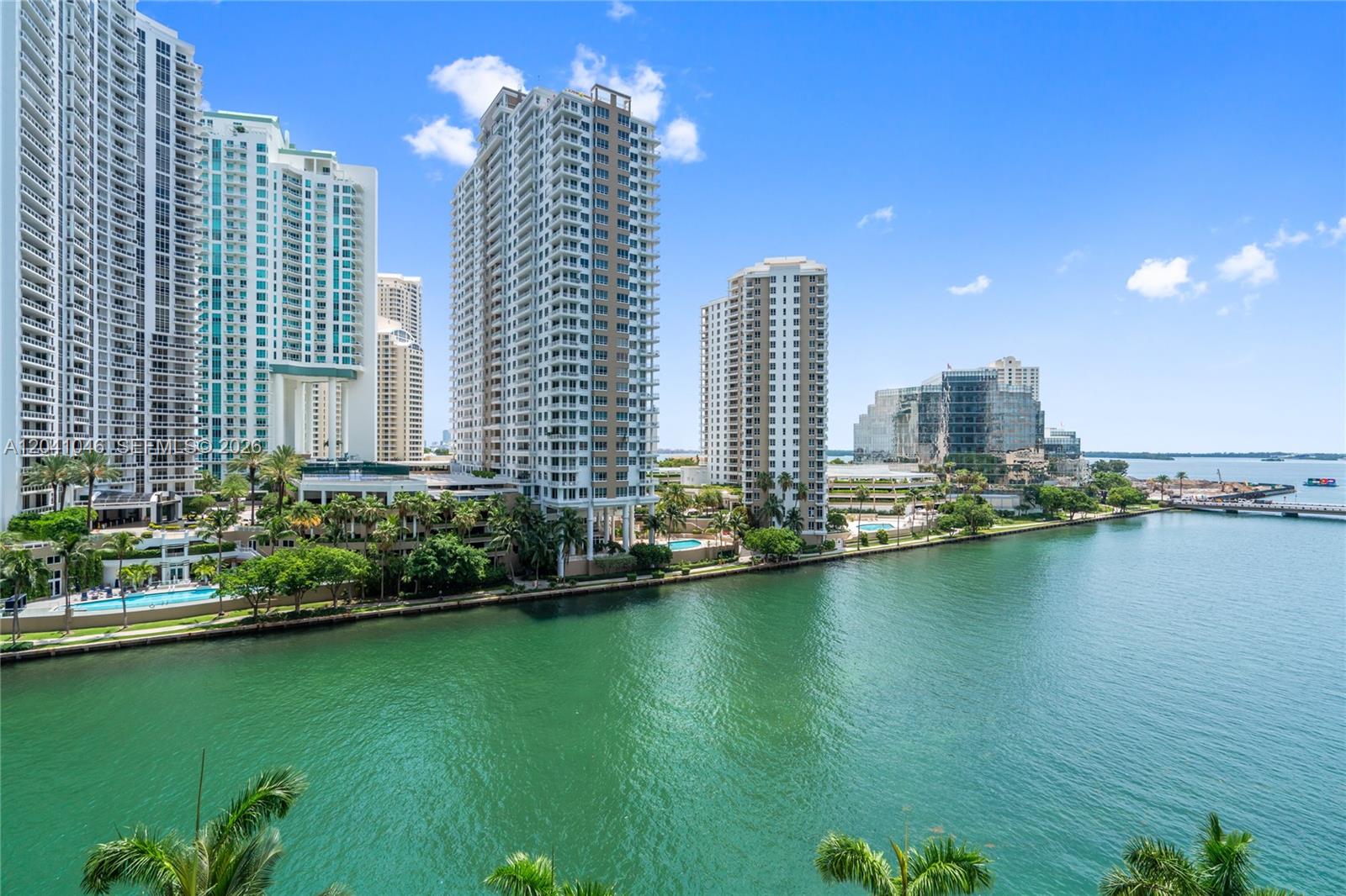 An elevated view of high-rise apartment buildings along a waterfront with palm trees and pools — 495 Brickell Ave, Miami FL 33131, MIAMI, FL