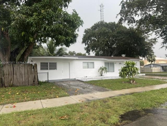 A white, single-story house with a flat roof, a wooden fence, and a paved driveway — 6901 Thomas St, Hollywood FL 33024, HOLLYWOOD, FL