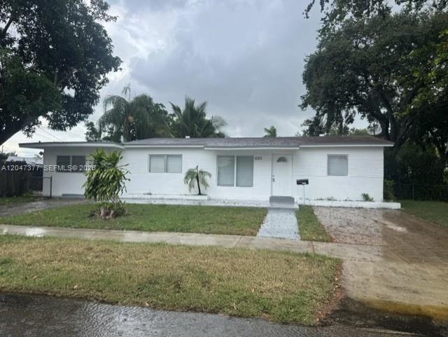 A single-story white house with a flat roof and a front lawn under a cloudy sky — 6901 Thomas St, Hollywood FL 33024, HOLLYWOOD, FL