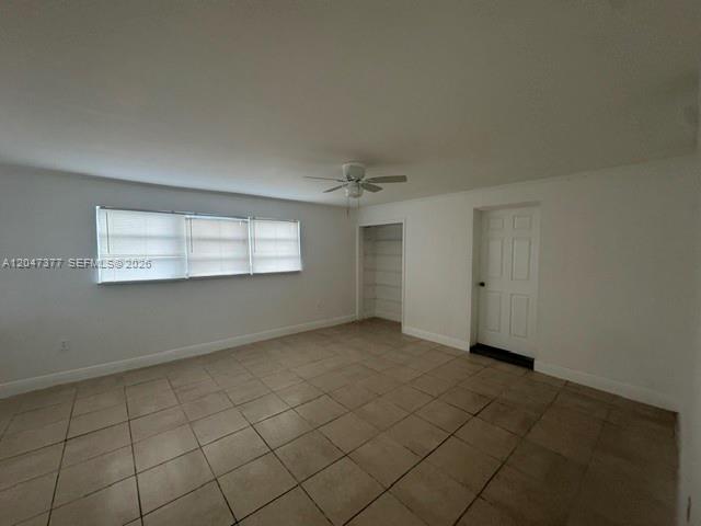 An empty room with beige tile flooring, a ceiling fan, and a window with blinds — 6901 Thomas St, Hollywood FL 33024, HOLLYWOOD, FL