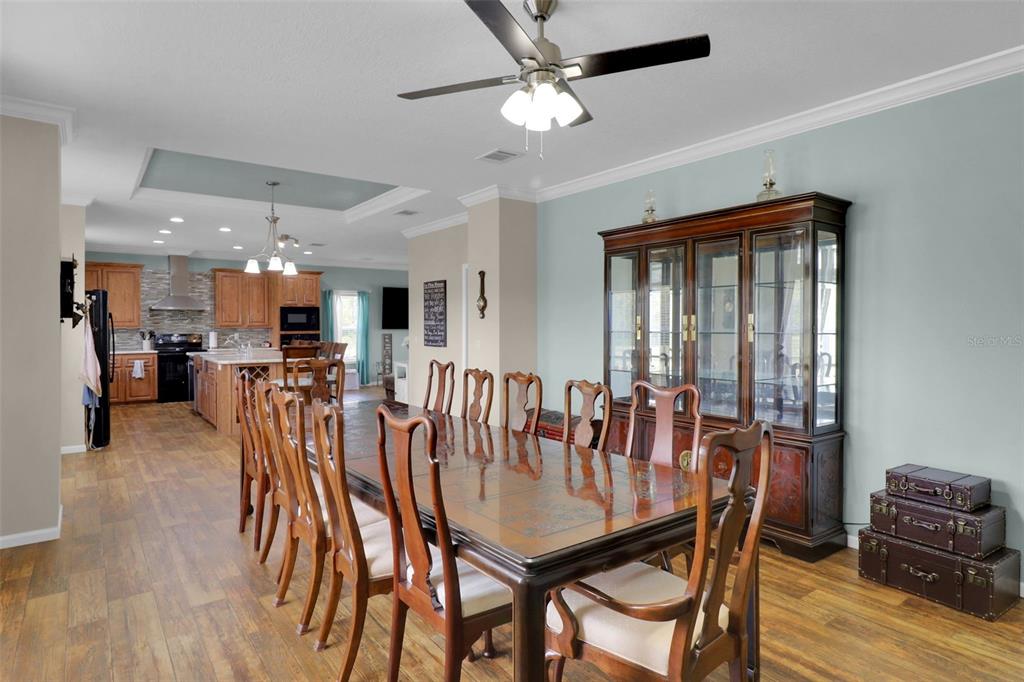 A dining room with a wooden table and chairs sits adjacent to an open kitchen — 16947 AUBURNDALE LANE, SPRING HILL, FL