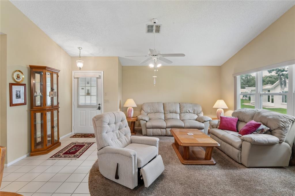 A living room features beige walls, carpeted flooring, a ceiling fan, and light-colored furniture — 4812 S SHEFFIELD DRIVE UNIT 5, NEW PORT RICHEY, FL