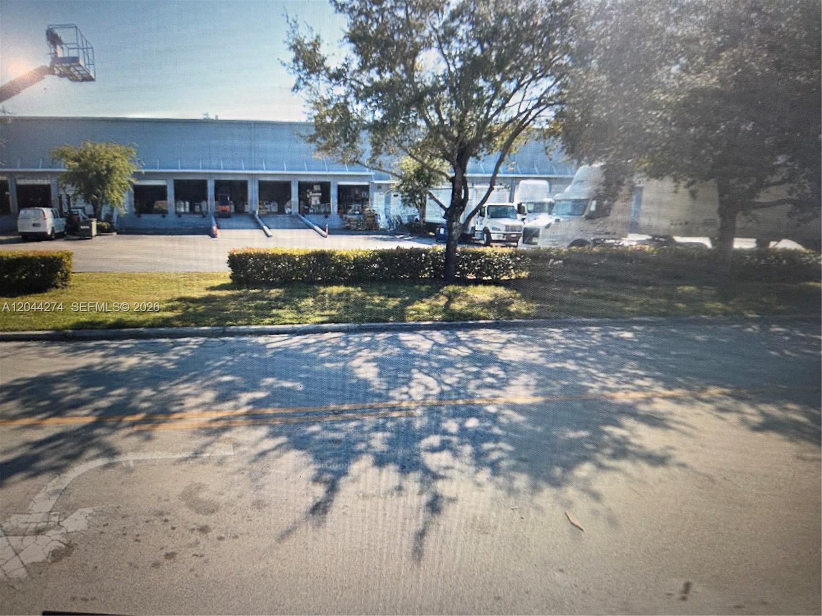 A view of a commercial warehouse building with loading docks and parked semi-trucks — 10871 NW 122nd St # 30, Medley FL 33178, MEDLEY, FL