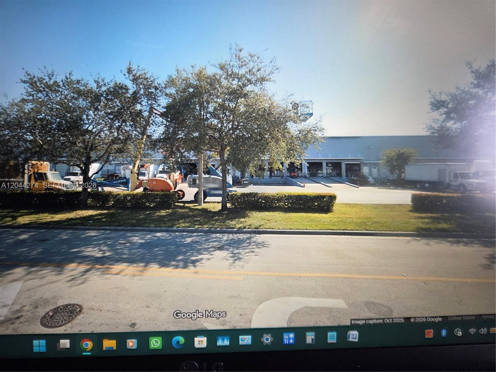 An exterior view of a commercial warehouse building with loading docks and parked construction equipment — 10871 NW 122nd St # 30, Medley FL 33178, MEDLEY, FL