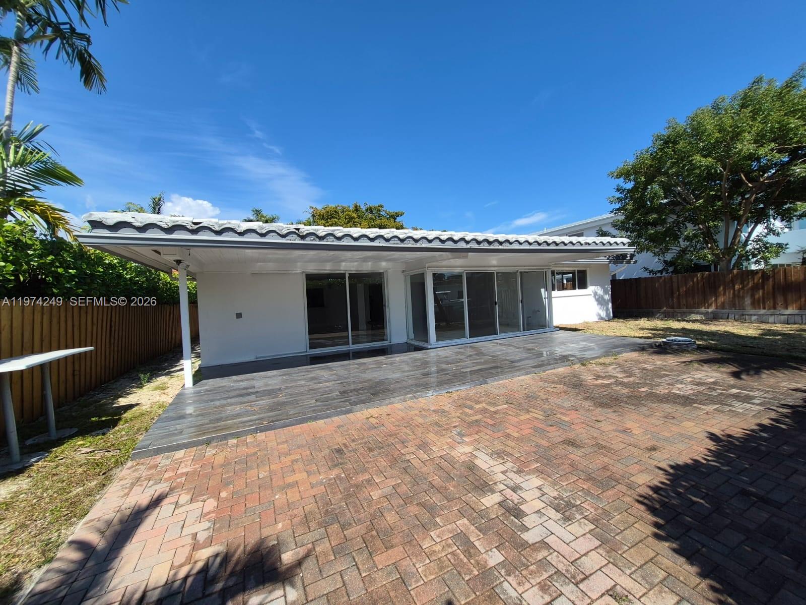 A white horizontal slat fence encloses the front yard of a single-story house — 1240 NE 83rd St # 1240, Miami FL 33138, MIAMI, FL