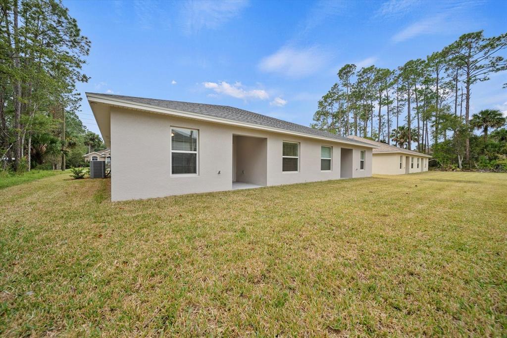 The exterior of a beige single-story house features a covered patio and a grassy yard — 43 PONCE DELEON DRIVE UNIT B, PALM COAST, FL