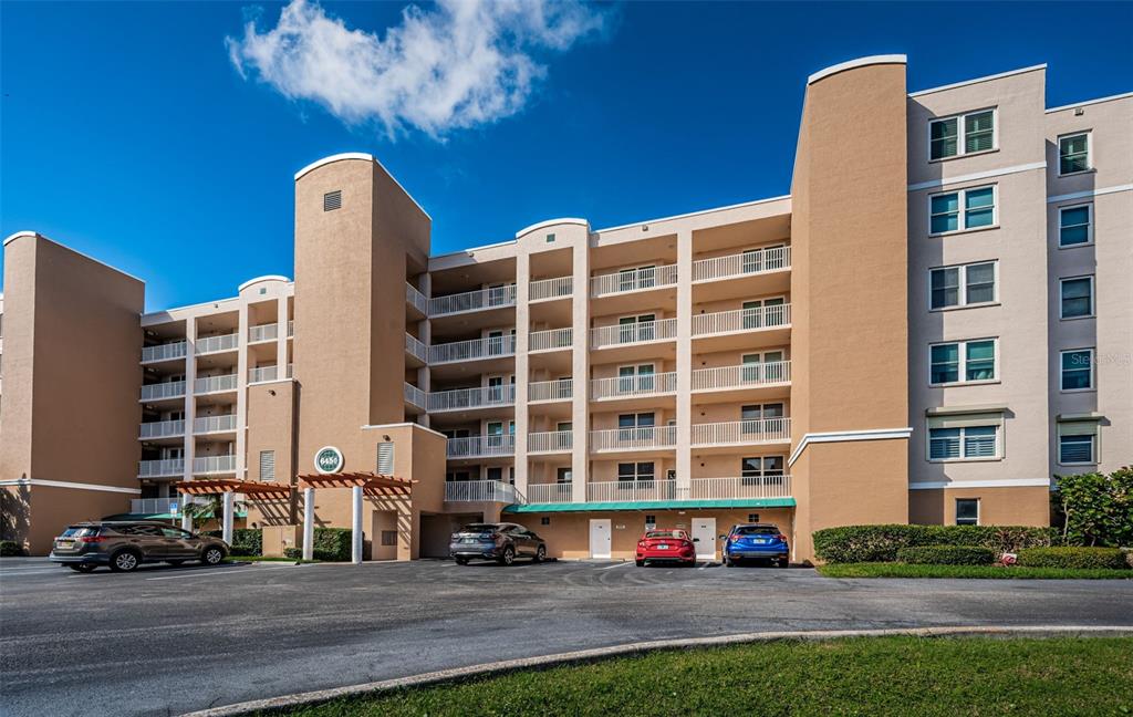 A multi-story tan apartment building with balconies and a parking lot in front — 6450 SHORELINE DRIVE UNIT 9203, ST PETERSBURG, FL